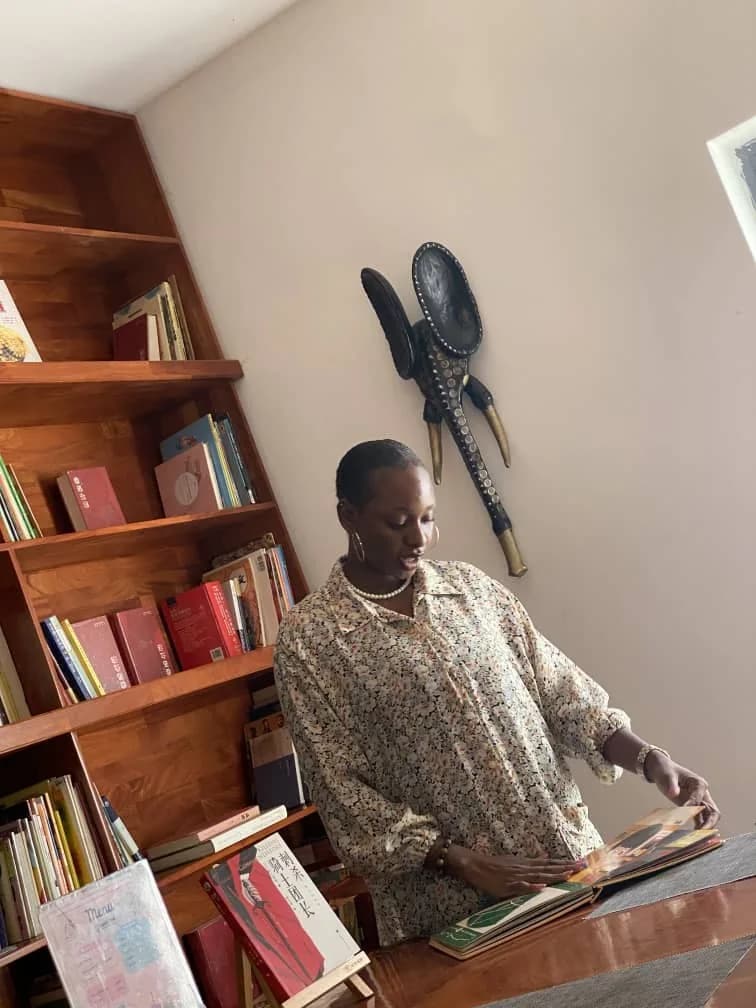 Peace leafing through a book beside a full bookshelf