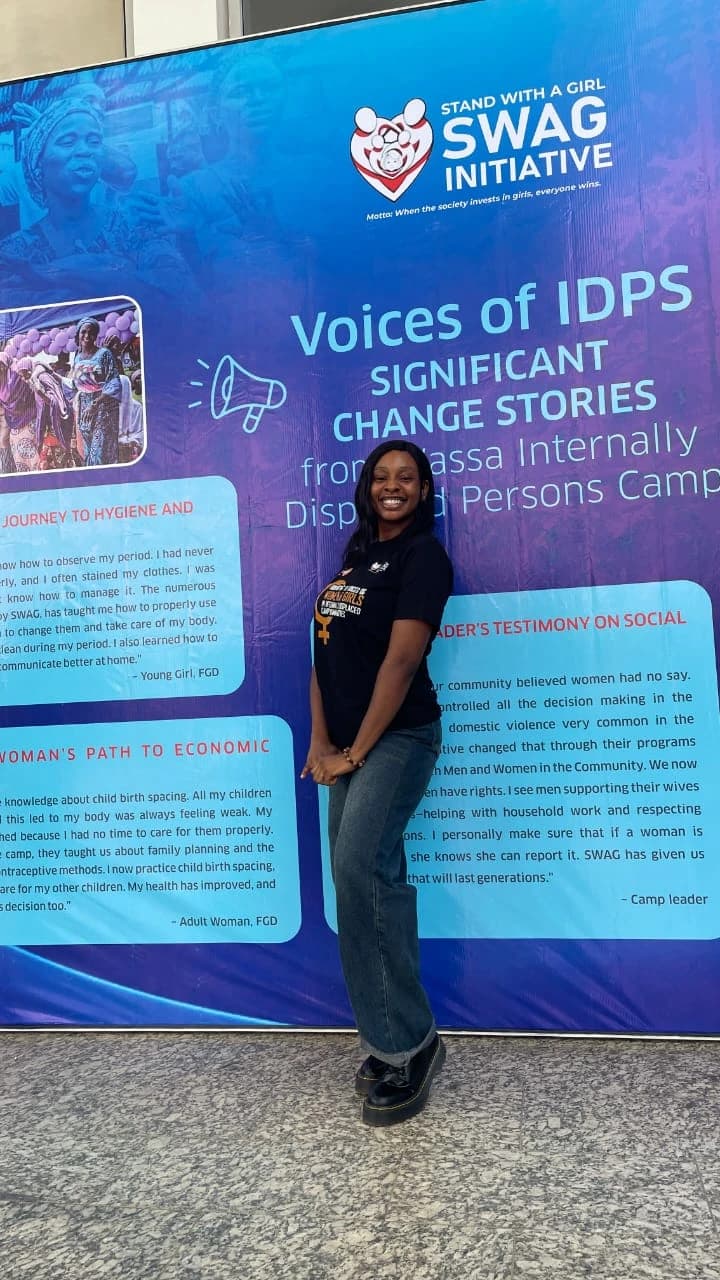 Peace smiling in front of the Voices of IDPs exhibition