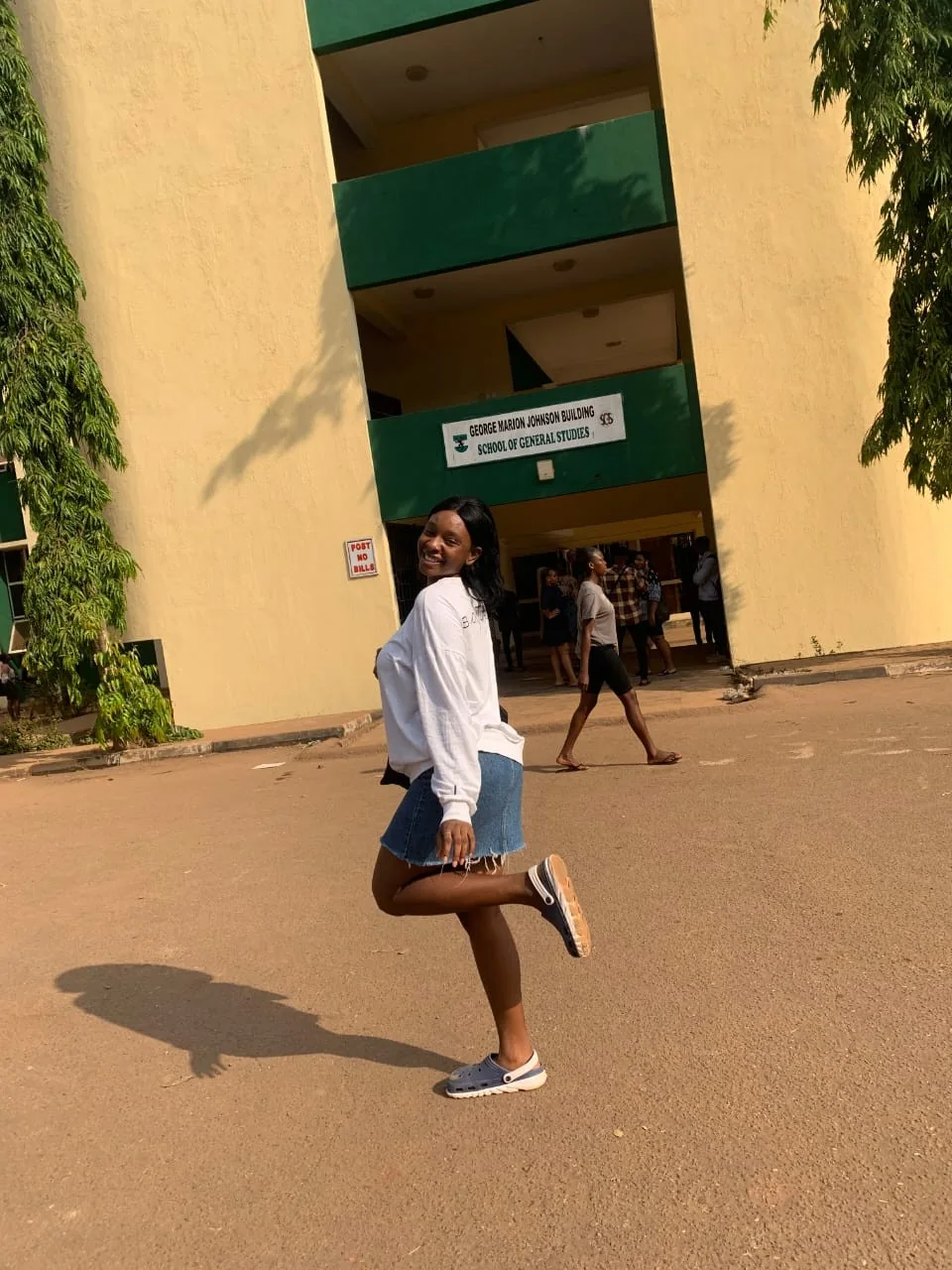 Peace mid-jump outside a lecture building